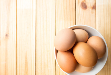 hen eggs in bowl on wood plate