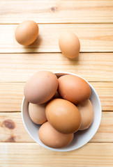 hen eggs in bowl on wood background