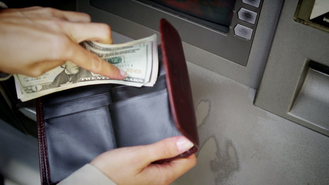 Close up of hands taking money from an ATM machine