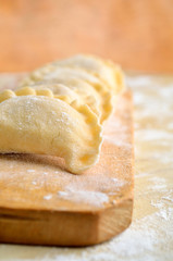 Sculpt pierogy and pelmeni concept. Include rustic cutting board, making pierogies on a rustic wooden table. Dumpling recipe. Close-up, shallow depth of field.