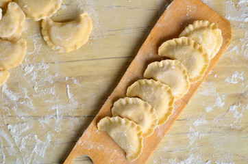 Sculpt pierogy and pelmeni concept. Include rustic cutting board, making pierogies on a rustic wooden table. Dumpling recipe.