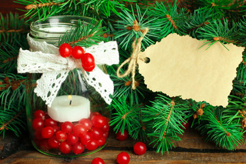 viburnum in a jar with a candle and a sprig of spruce on a wooden table