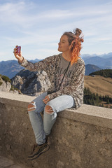 Teenager auf der Mauer sitzend, macht eine Selfie-Aufnahme in de