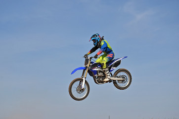 Motocross rider flying high on against a blue sky in the air separately