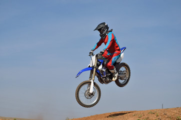 Motocross athlete on a motorcycle motocross jumps down from the hill sideways
