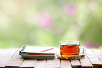 tea in glass and notebook with pencil at windows
