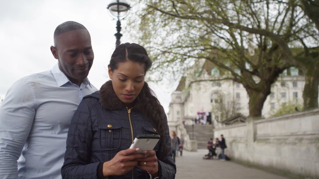  Happy couple sightseeing in London taking a selfie on smartphone.