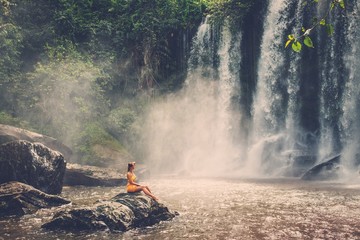 Beautiful woman sitting near waterfall enjoying the sun, Phnom Koulen at Siem Reap, Cambodia