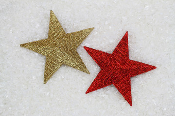 Fototapeta na wymiar Red and golden stars covered with glitter on snowy surface 