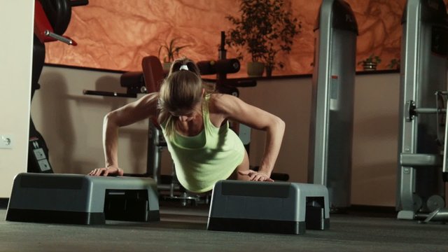 The woman does push-ups on fitness steps