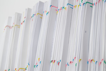 Colorful paper clip with pile of overload paperwork and reports place verlical