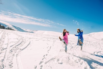 winter, two cheerful young girls having fun in the snow in the m