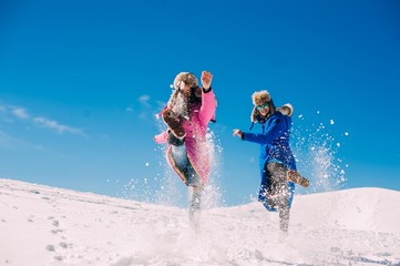 winter, two cheerful young girls having fun in the snow in the m