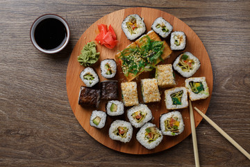 Fototapeta na wymiar Sushi set at round wooden plate 