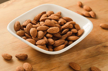Healthy snack almond kernels in white bowl