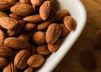 Healthy snack almond kernels in white bowl
