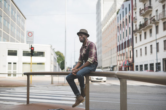 young handsome afro black man sitting on a handrail outside in t