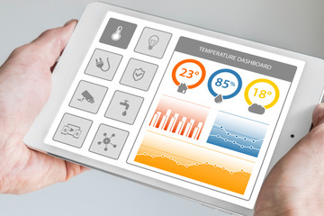 Smart home dashboard in order to control home appliances. Hand holding modern tablet with dashboard...