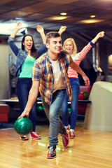 happy young man throwing ball in bowling club