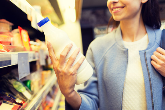 happy woman holding milk bottle in market
