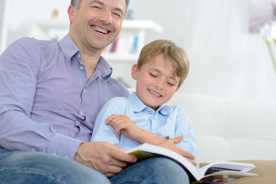 Father and son laughing while reading book