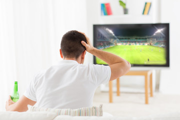 man watching football and drinking beer at home