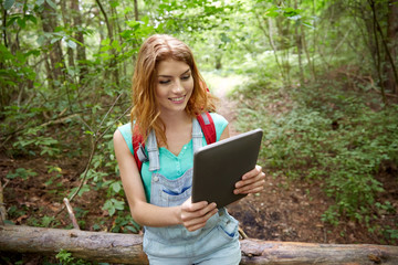 Obraz premium happy woman with backpack and tablet pc in woods
