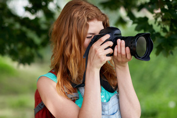 young woman with backpack and camera outdoors