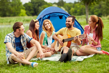 Fototapeta premium happy friends with drinks and guitar at camping