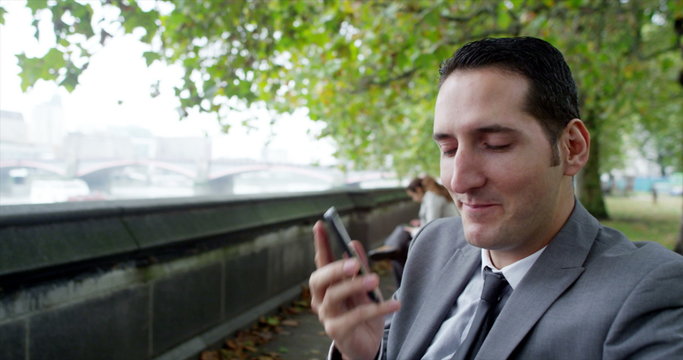  Portrait of young businessman making phone call beside London's River Thames