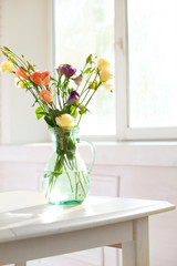 Beautiful spring flowers in vase on window background