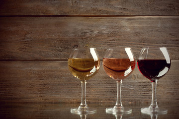 Glasses with white, rose and red wine on wooden background