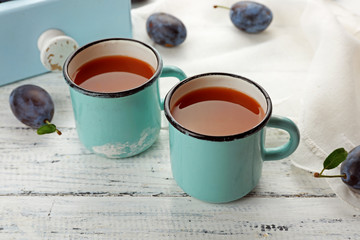 Plum Juice in mugs with fresh fruits