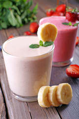 Glasses of fresh cold smoothie with fruit and berries, on wooden background