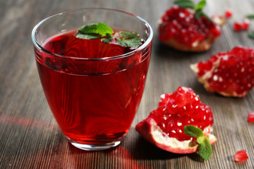 A glass of tasty juice and garnet fruit, on wooden background