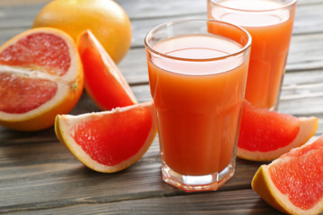 Glass of grapefruit juice and fresh fruits on wooden background