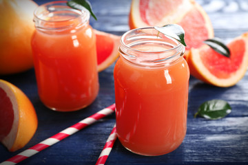 Grapefruit juice in bottles and fresh fruits on dark blue wooden background