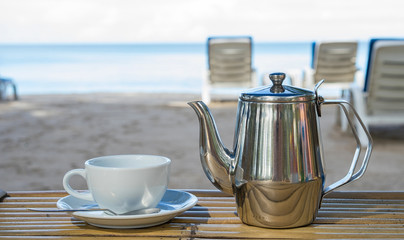 Cup and pot of tea in the bamboo table on the beach