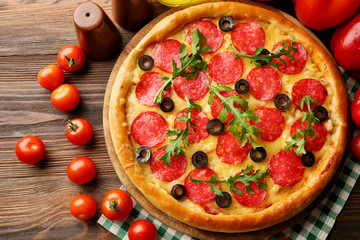 Tasty pizza with salami on decorated wooden table