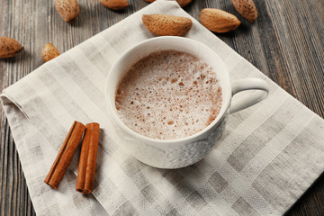 Cup of hot cacao on cotton serviette with cinnamon and almonds