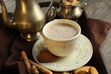 Vintage cup of cacao on tray with silver service and cookies