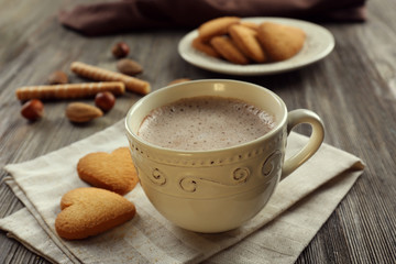 Cup of hot cacao on cotton serviette with cinnamon, almonds and heart shaped cookies