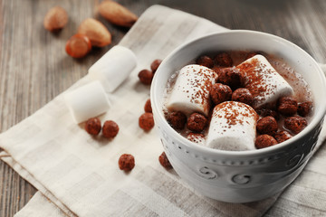 Cup of hot cacao with marshmallow on cotton serviette, close up