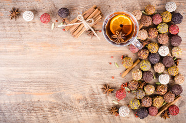 Handmade chocolate candies collection, dried oranges, cinnamon, cloves, cardamom, mulled wine on wooden background. Free space for your text.