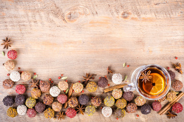 Handmade chocolate candies collection, dried oranges, cinnamon, cloves, cardamom, mulled wine on wooden background. Free space for your text.