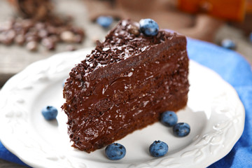 Chocolate cake with chocolate cream and fresh blueberries on plate, on wooden background