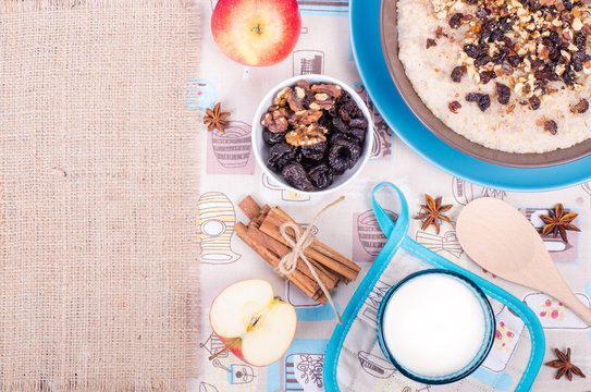 Breakfast set. A bowl of barley porridge with cocnut oil, vegetarian milk, walnuts, raisins, cinnamon on sackcloth, canvas, spoon, apple, glass of vegetarian milk. Free space for your text.