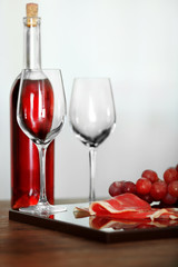 Pink wine bottle, two wineglasses, grape, slice of bacon on a table, still life