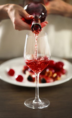 Young woman pouring pink wine into glass on the table