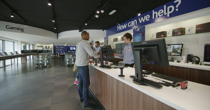 Salesman taking payment from customer in consumer electronics store showroom